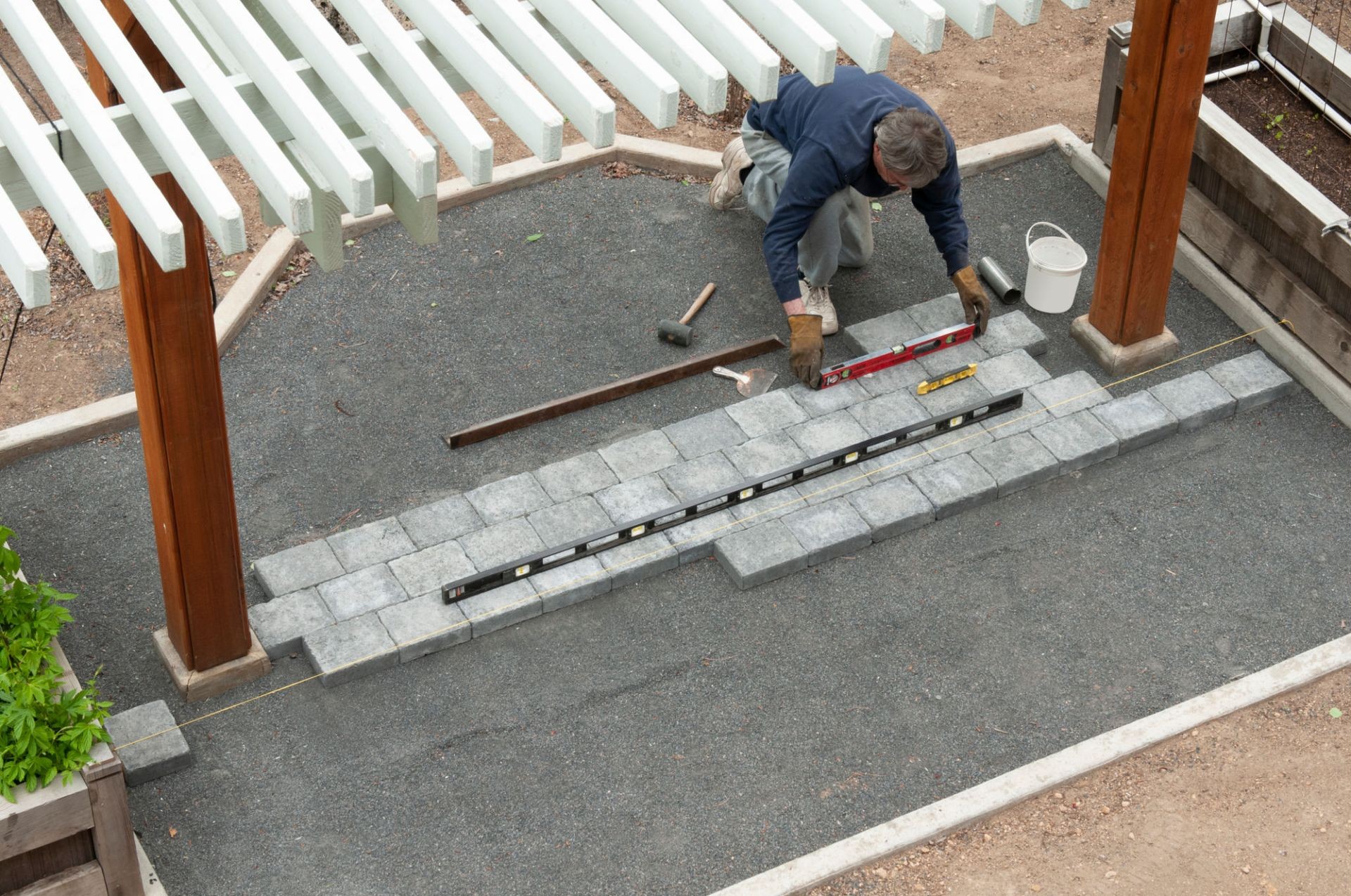 Worker installing decorative concrete pavers for a stylish outdoor patio.